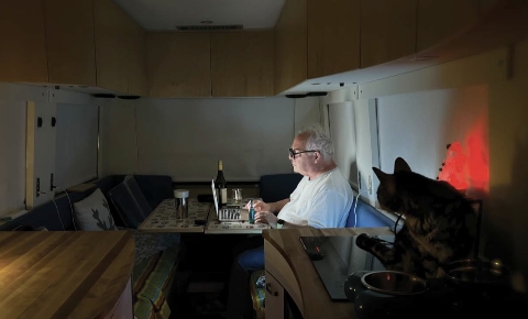 Luc Senay au travail dans l’intimité de son autocaravane. - Camping Caravaning